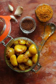 some food is in a glass bowl on a table with spices and spoons next to it