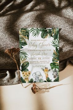 a baby shower with jungle animals and leaves on it's back, next to a t - shirt