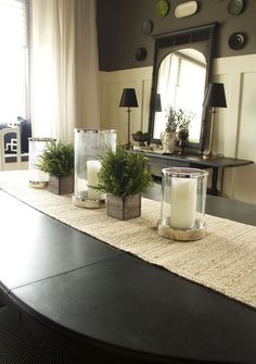 candles and plants on a table with a mirror in the background