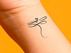 a small tattoo on the wrist of a woman's arm that has scissors in it