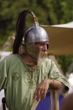 a man wearing a helmet and holding a stick in his right hand while sitting on a chair