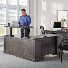 a man standing at a desk using a laptop computer