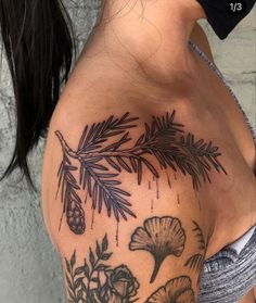 the back of a woman's shoulder with flowers and pine cones on it