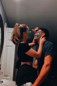 a man and woman are in the bathroom with their faces covered by masks while they look into each other's eyes