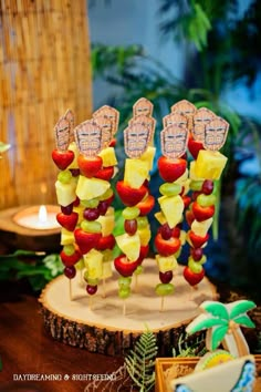 fruit skewers are arranged in the shape of people's hands on a tree stump