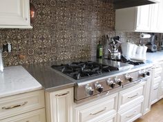 a stove top oven sitting inside of a kitchen next to white cabinets and counter tops