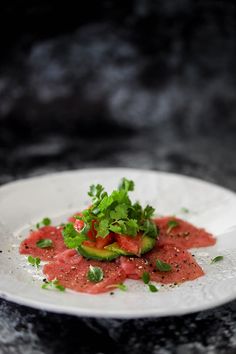 a white plate topped with food on top of a black counter next to a knife