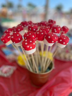 red and white cake pops with polka dots in a brown cup on a pink table cloth