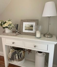 a white table with flowers and pictures on it next to a lamp, vases and other items