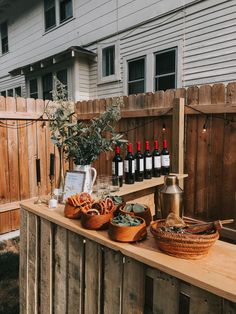 a wooden table topped with lots of bottles of wine next to a potted plant