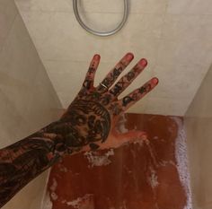 a person's hand with tattoos on it is in the air above a toilet