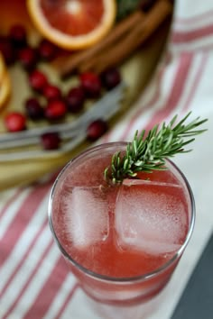 a close up of a drink in a glass with ice and cranberries on the side