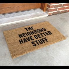 a door mat that says the neighbors have better stuff on it in front of a red brick building