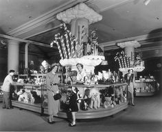 an old black and white photo of people standing in front of a candy shop display