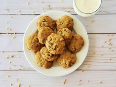 a white plate topped with chocolate chip cookies next to a glass of milk