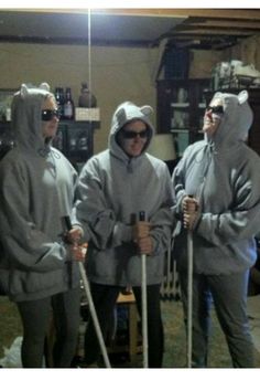 three people in grey hoodies holding canes