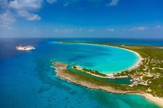 an island in the middle of the ocean with a cruise ship on it's side