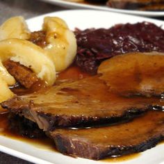 a white plate topped with meat and gravy next to sliced banana's