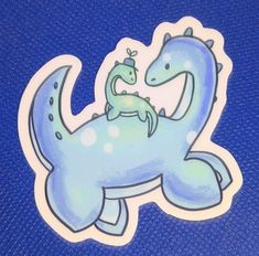 a blue sticker with an image of a dinosaur holding a baby lizard on it's back