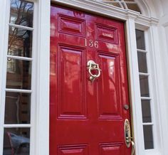 a red front door with two windows and a number on the bottom one is painted gold