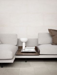 a white couch sitting next to a table with a book on top of it in front of a wall