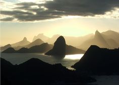 the sun shines brightly through clouds over mountains and water on an island in the ocean