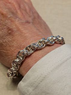 a person wearing a silver chain bracelet on their arm