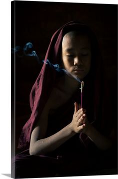 Stretched Canvas Print entitled Novice Monk Holding A Lit Incense Stick While Praying Inside A Temple, Bagan, Myanmar.  Novice monk holding a lit incense stick while praying inside a temple, UNESCO, Bagan, Mandalay Region, Myanmar.  Multiple sizes available.  Primary colors within this image include Black, Light Gray, Gray.  Made in the USA.  Satisfaction guaranteed.  Archival-quality UV-resistant inks.  Museum-quality, artist-grade canvas mounted on sturdy wooden stretcher bars 1.5 thick.  Come Bagan Myanmar, Black Framed Wall Art, Bagan, Mandalay, Large Canvas Prints, Incense Sticks, Big Canvas Art, Great Big Canvas, Black Light