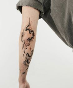 a man with a dragon tattoo on his arm and leg, leaning down to the side