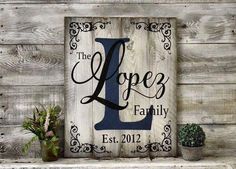 a wooden sign with the letter l on it next to potted plants and succulents