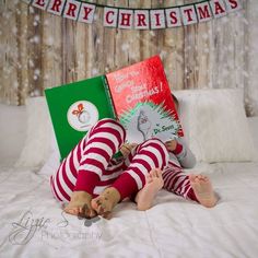 a woman laying on top of a bed next to a christmas tree and two books