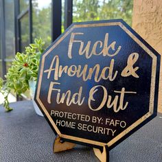 a black and gold stop sign sitting on top of a table next to a potted plant