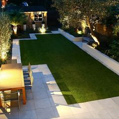 an outdoor dining area is lit up at night with lights on the walls and lawn