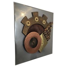 a metal wall hanging with an abstract design on it's face and two circular holes in the middle