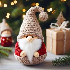 a crocheted santa clause ornament sitting next to a christmas tree