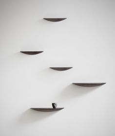 three black shelves are arranged in the shape of an arrow and one is shaped like a bird