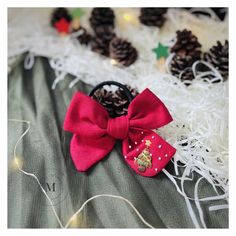 a red bow with pine cones on it sitting next to some string lights and other decorations