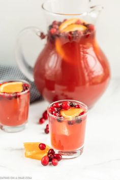 two glasses filled with cranberry punch and garnished with orange wedges