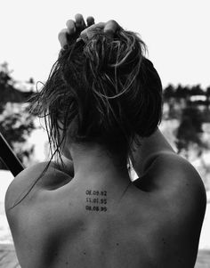 the back of a woman's neck with numbers tattooed on her left upper arm