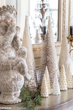 christmas trees are sitting on a mantle in front of a mirror and an elephant statue