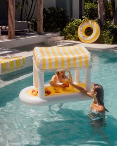 two children playing in the pool with an inflatable water table and umbrellas