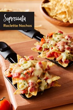 two nachos with cheese, tomatoes and other toppings on a cutting board