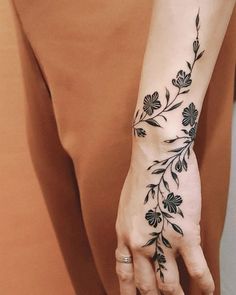 a woman's hand with a flower tattoo on her left arm and the wrist