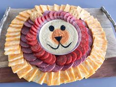 a platter with cheese, meat and crackers in the shape of a lion's face