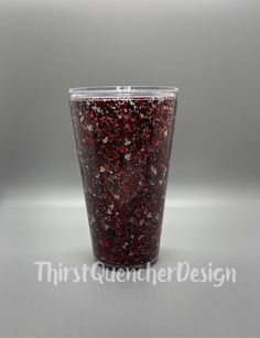 a plastic cup filled with red stuff on top of a white table next to a gray wall