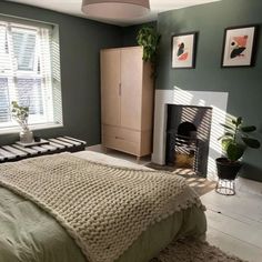 a bed room with a neatly made bed next to a window and a fire place