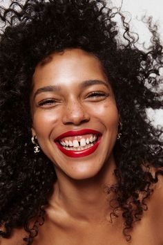 a smiling woman with curly hair and red lipstick