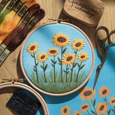 embroidery kit with sunflowers and scissors on wooden table next to thread spools