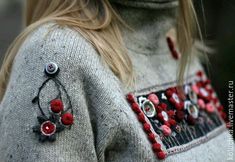 a close up of a person wearing a sweater with red flowers on the front and side