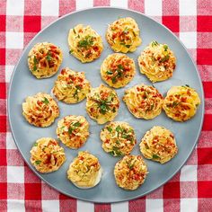 a plate full of small appetizers on a red and white checkered table cloth